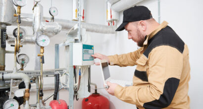 heating equipment inspecting. engineer or plumber inspector in boiler room taking readouts or adjusting heat meter